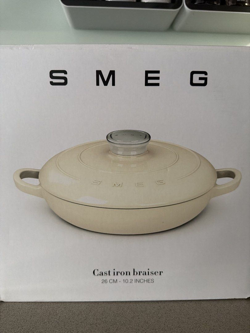 SMEG Cast Iron Braiser 26cm - Cream (Category: Cookware & Accessories) located in Singapore. Submitted by ml_brow (Listing ID 1440302666, Image 1). Description: - SMEG Cast Iron Braiser - Size: 26cm (10.2 inches) - Color: Cream - Oven Safe: Up to 260°C - Hob Compatibility: Induction - Ideal for: Slow cooking, braising - Includes: Glass lid, original box.