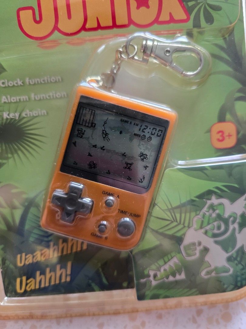 Game & Watch - Donkey Kong Junior (Category: Interactive Toys) located in Singapore. Submitted by ButterCup (Listing ID 1455942890, Image 2). Description: - Nintendo Game & Watch Mini Classics - Features Donkey Kong Junior - Original packaging included - Orange handheld console - Functions as a game, clock, and alarm - Can be used as a keychain - Collectible retro gaming item.