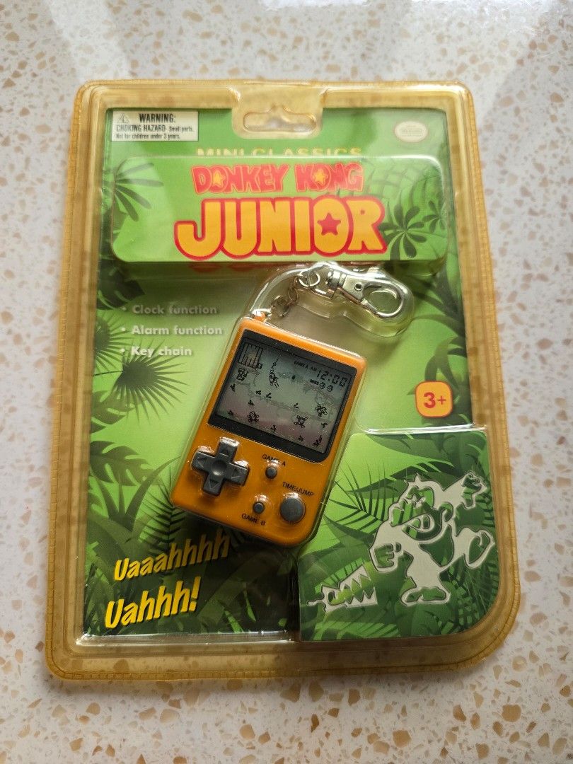 Game & Watch - Donkey Kong Junior (Category: Interactive Toys) located in Singapore. Submitted by ButterCup (Listing ID 1455942890, Image 1). Description: - Nintendo Game & Watch Mini Classics - Features Donkey Kong Junior - Original packaging included - Orange handheld console - Functions as a game, clock, and alarm - Can be used as a keychain - Collectible retro gaming item.