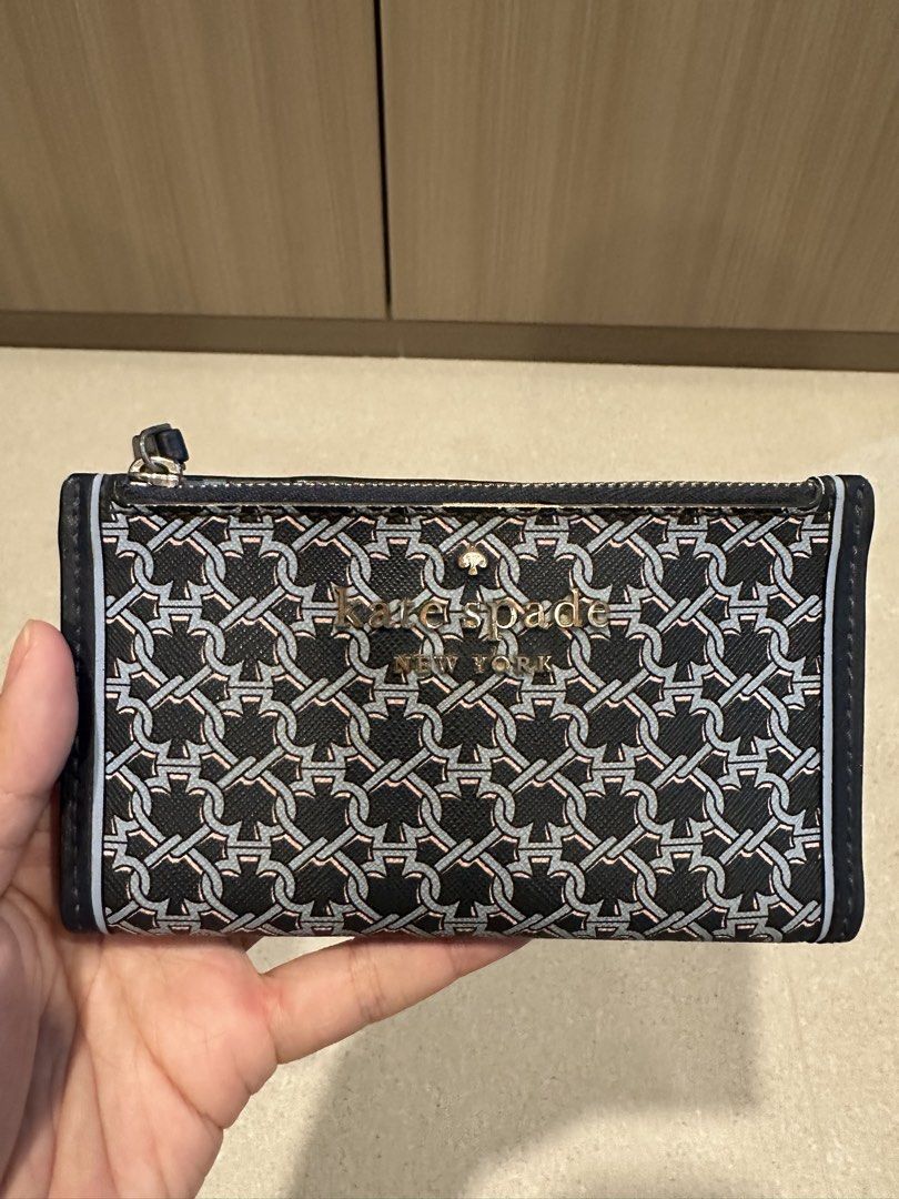 Kate Spade Blue link patterned lock bi fold card holder wallet (Category: Wallets & Card Holders) located in Singapore. Submitted by whitespade_ (Listing ID 1456009460, Image 2). Description: - Brand: Kate Spade - Type: Bi-fold card holder wallet - Design: Blue link pattern with gold 'Kate Spade New York' logo - Interior: Multiple card slots, clear ID window, zippered compartment, able to put coins and cards - Color: Blue and navy - Features: Com