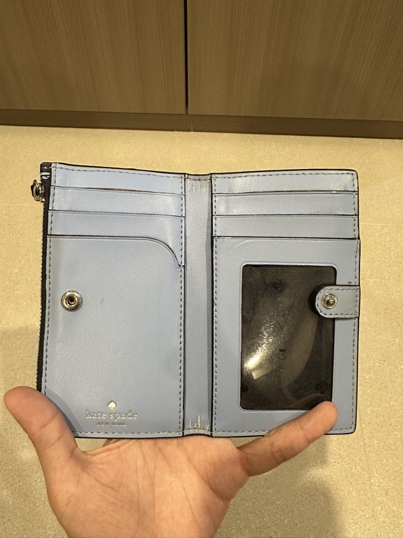 Kate Spade Blue link patterned lock bi fold card holder wallet (Category: Wallets & Card Holders) located in Singapore. Submitted by whitespade_ (Listing ID 1456009460, Image 4). Description: - Brand: Kate Spade - Type: Bi-fold card holder wallet - Design: Blue link pattern with gold 'Kate Spade New York' logo - Interior: Multiple card slots, clear ID window, zippered compartment, able to put coins and cards - Color: Blue and navy - Features: Com