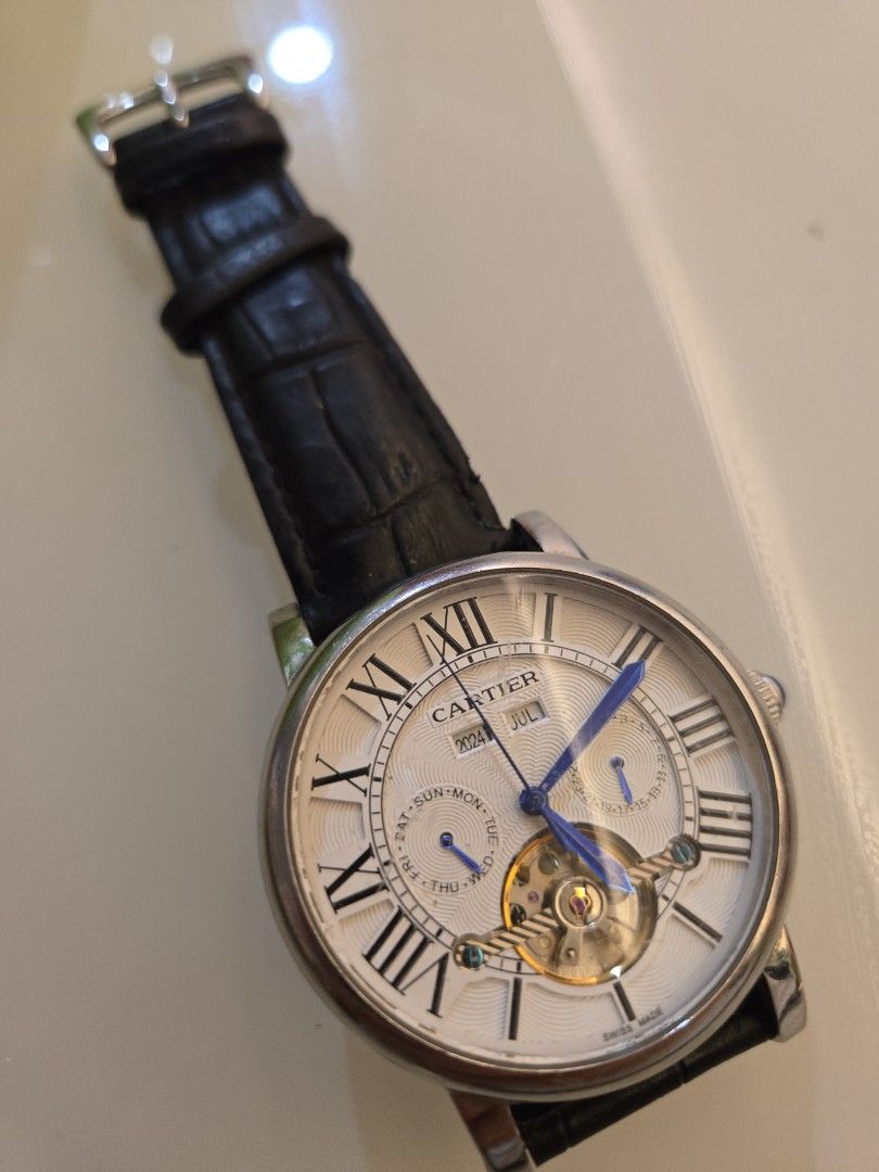 Automatic Watch with Leather Strap (Category: Men's Watches) located in Singapore. Submitted by urban.trader (Listing ID 1458056027, Image 1). Description: - Cartier automatic watch - Visible balance wheel showcasing the movement - Classic Roman numeral dial - Day and year is static - Date is working. - Comes with a blue leather strap and buckle - Exhibition case back to view the movement.