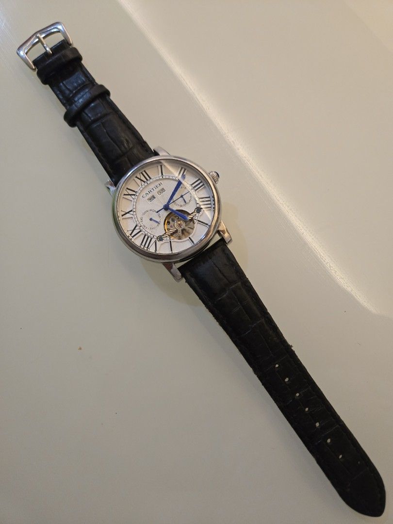 Automatic Watch with Leather Strap (Category: Men's Watches) located in Singapore. Submitted by urban.trader (Listing ID 1458056027, Image 2). Description: - Cartier automatic watch - Visible balance wheel showcasing the movement - Classic Roman numeral dial - Day and year is static - Date is working. - Comes with a blue leather strap and buckle - Exhibition case back to view the movement.